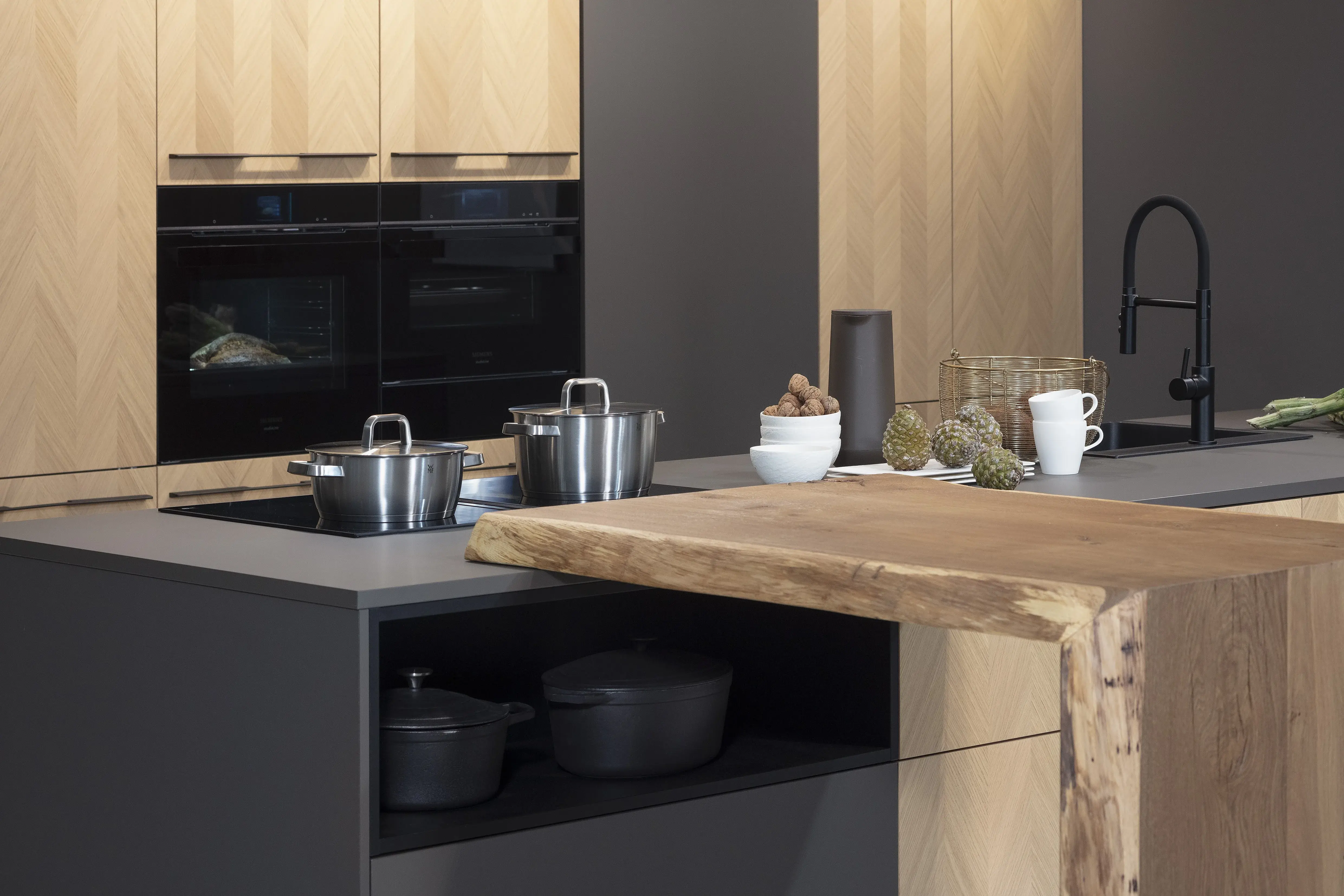 Front: Intarsia Gavi Eiche Furnier Resopal Brown Powder supermatt Korpus Schwarz APL: Resopal Brown Powder supermatt Geräte: Siemens Studio Line Spüle und Armatur: Blanco   Features: Front Echtholz Fischgrät-Optik, Kombination Echtholz und Resopal supermatt, Einbautür in Frontmaterial Resopal, Küchentheke Massivholz, APL = Korpusfarbe = Frontmaterial, Kombination Griffleiste und grifflos, Korpus in Frontmaterial, Wärmeschublade, Spüle und Armatur Schwarz, Besteckeinsatz. 