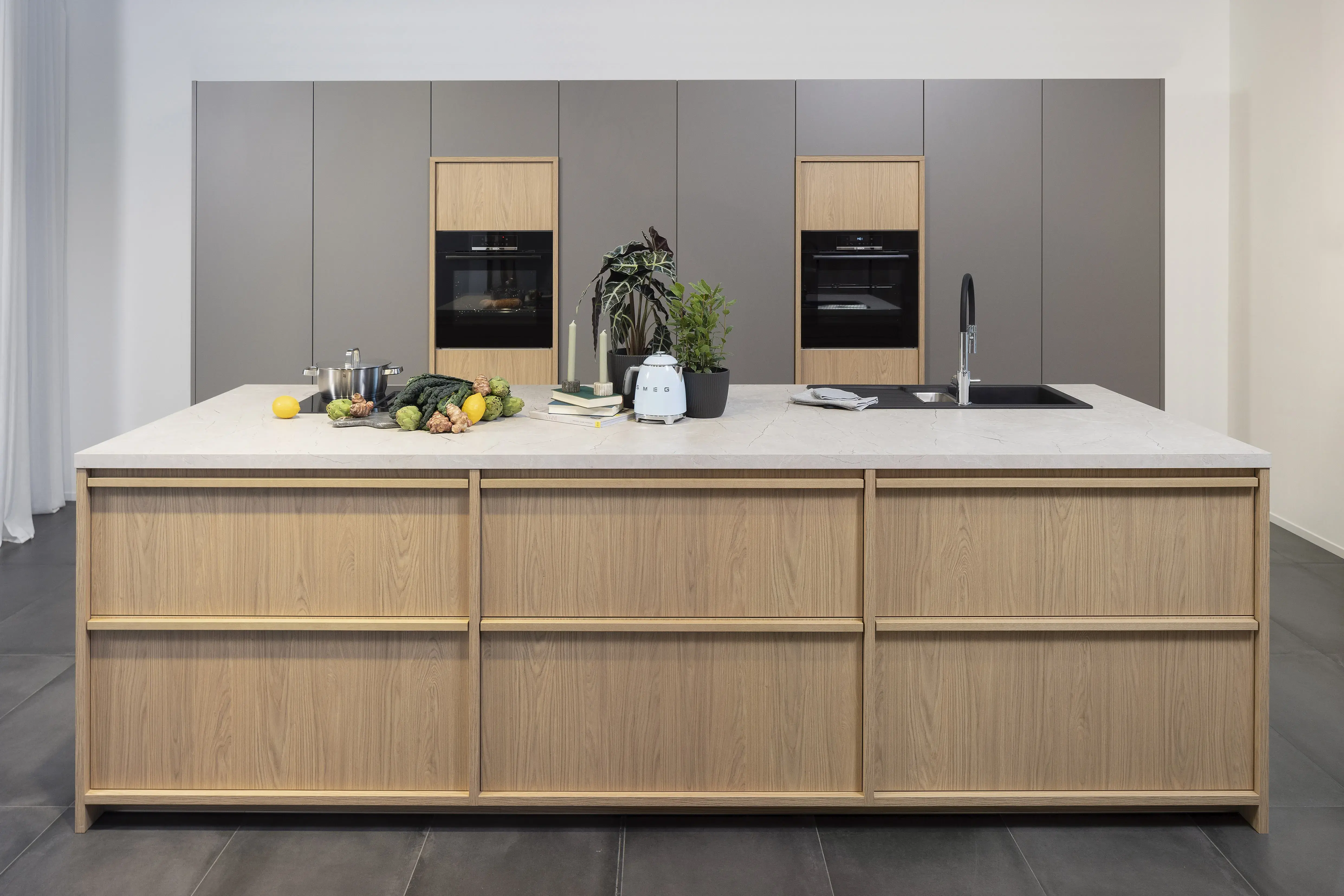 Moderne Küche mit großer Holzinsel, Obst, Kräutern und integriertem Backofen.